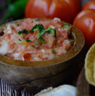 pico de gallo surrounded by tomatoes, garlic, peppers, and tortillas
