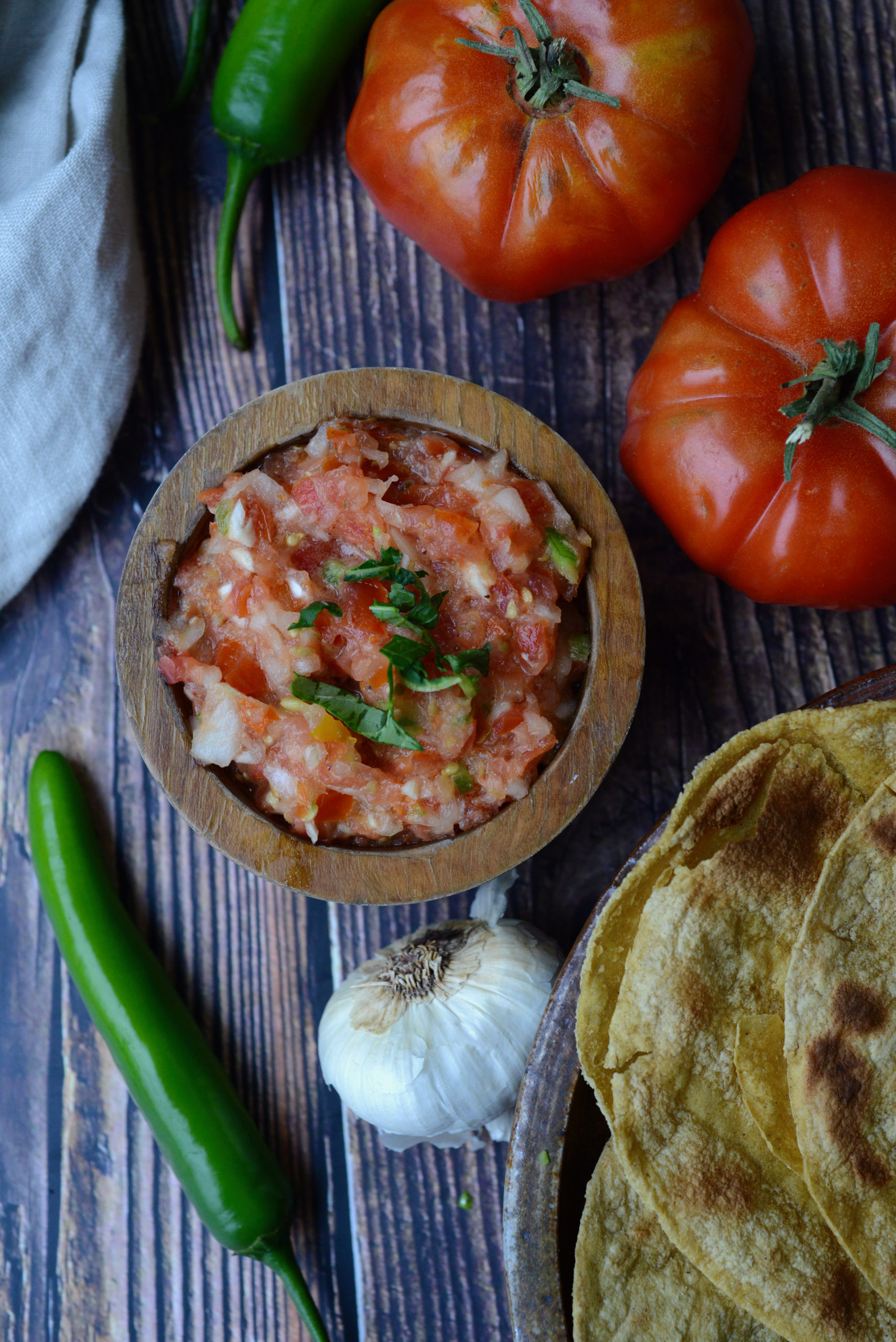 Pico de Gallo [Fresh Raw Salsa] surrounded by tomatoes, garlic, peppers, and toasted tortillas