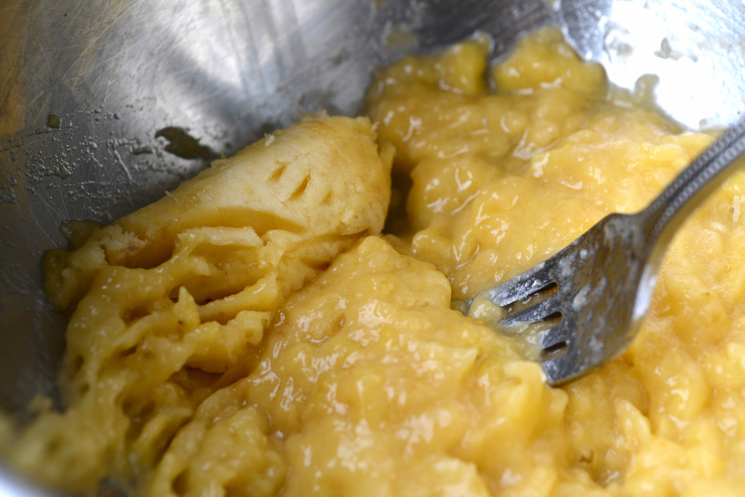 closeup of mashed bananas in bowl with fork