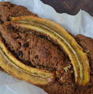 Whole loaf of baked fruit-sweetened healthy vegan banana bread in parchment paper
