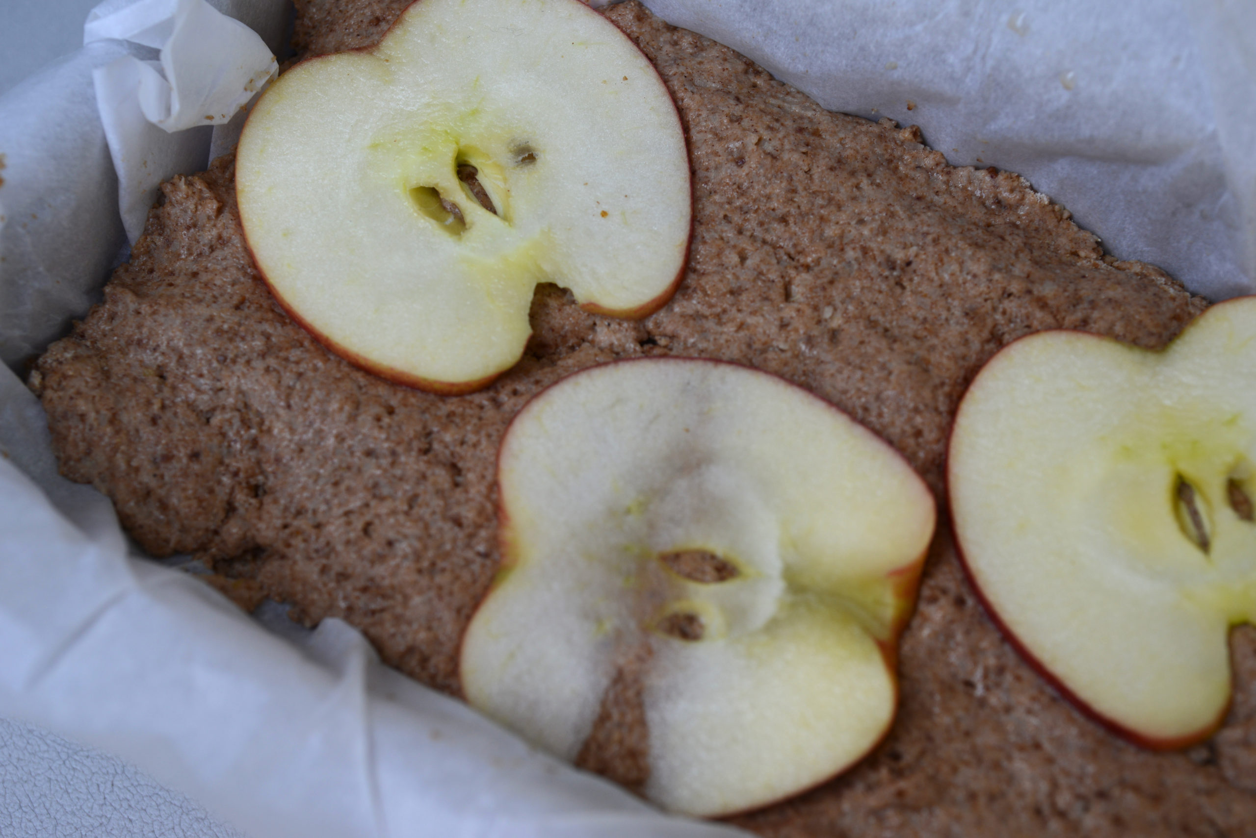 vegan apple bread batter pressed into loaf pan and topped with thin raw apple slices