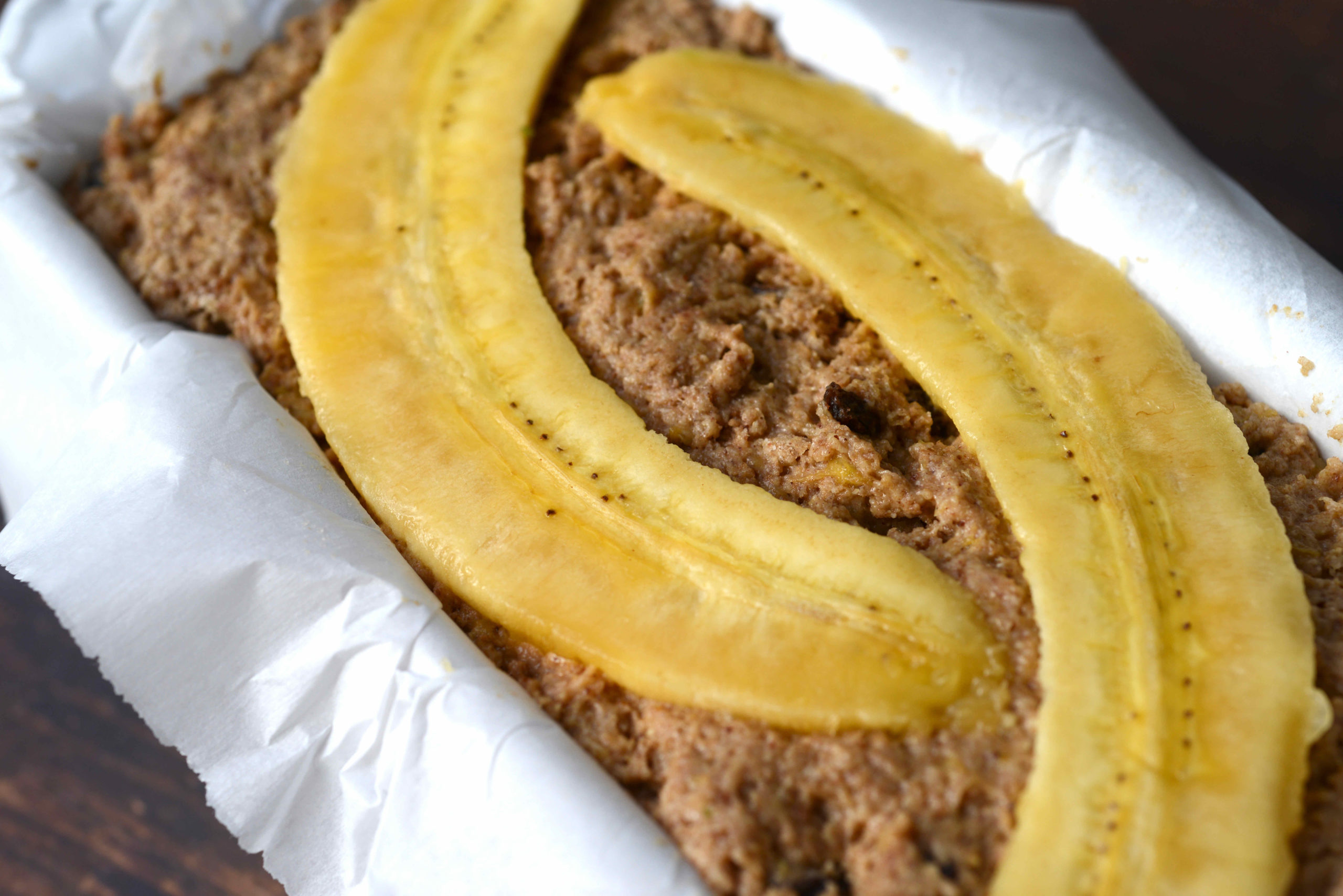 closeup of Fruit-Sweetened Healthy Vegan Banana BreadFruit-Sweetened Healthy Vegan Banana Bread unbaked in loaf pan topped with sliced bananas